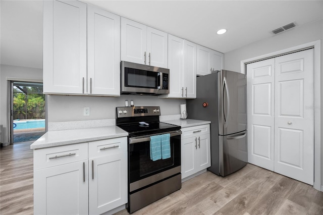 2726 Knoll St E, Palm Harbor, FL 34683 - kitchen featuring stainless steel appliances, white cabinetry, light wood-type flooring, recessed lighting, and light stone counters