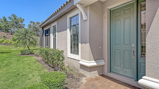 entrance to property with stucco siding and a yard
