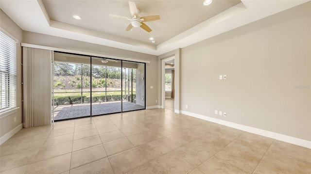 empty room featuring a raised ceiling, a ceiling fan, light tile patterned flooring, baseboards, and recessed lighting
