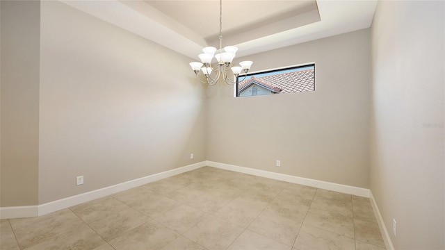 unfurnished room featuring a chandelier, a tray ceiling, baseboards, and light tile patterned floors