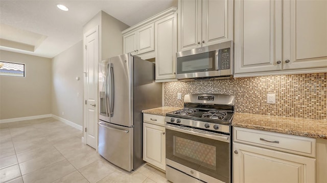 kitchen with stainless steel appliances, backsplash, baseboards, light stone counters, and light tile patterned floors