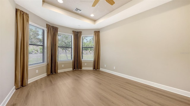 spare room with light wood-type flooring, a raised ceiling, baseboards, ceiling fan, and recessed lighting