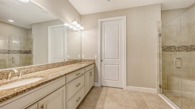 bathroom featuring a shower stall, double vanity, baseboards, tile patterned flooring, and recessed lighting