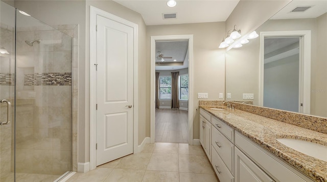 bathroom featuring a shower stall, double vanity, baseboards, and tile patterned flooring