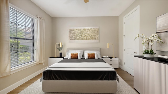 bedroom featuring wood finished floors, baseboards, and a ceiling fan
