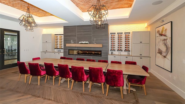 dining area featuring a raised ceiling, a chandelier, wood finished floors, and a fireplace