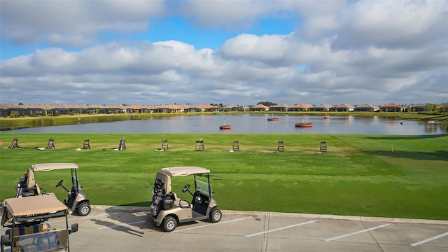 view of property's community with a residential view, a water view, uncovered parking, and a lawn