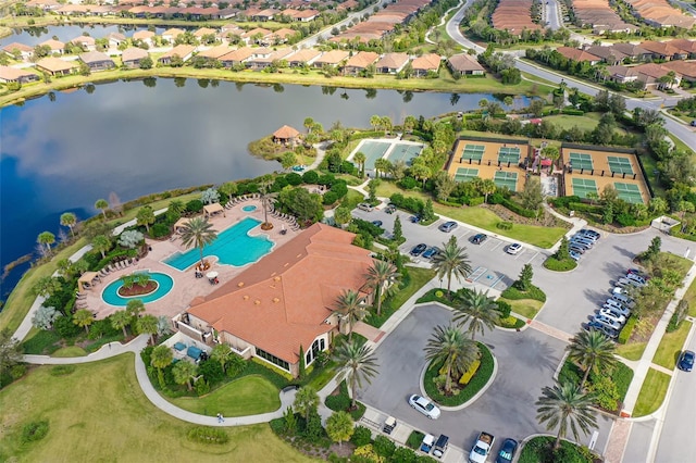 aerial overview of property's location with a nearby body of water, a pool, and nearby suburban area