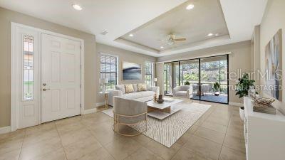 12619 Sorrento Way, Bradenton, FL 34211 - living room featuring baseboards, a tray ceiling, light tile patterned flooring, a ceiling fan, and recessed lighting