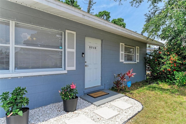 doorway to property featuring a yard and concrete block siding