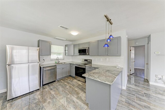 kitchen with appliances with stainless steel finishes, gray cabinetry, a sink, a peninsula, and light stone counters