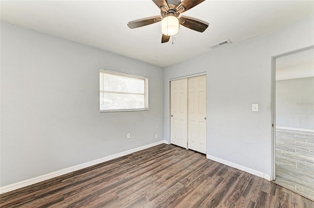 unfurnished bedroom with dark wood-type flooring, baseboards, a closet, and ceiling fan