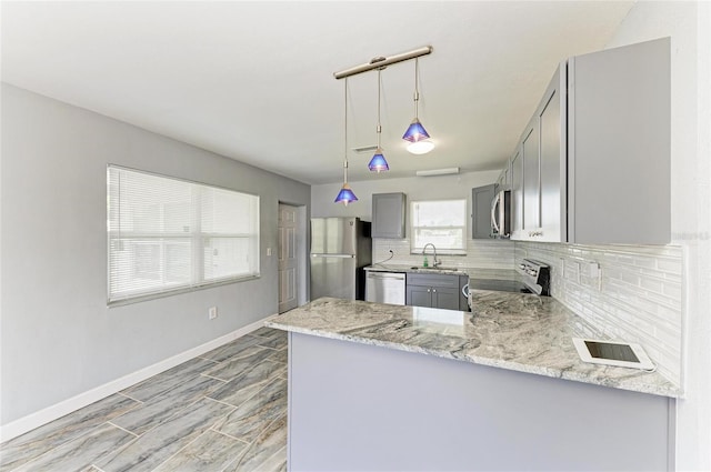 kitchen featuring stainless steel appliances, gray cabinetry, a sink, tasteful backsplash, and baseboards