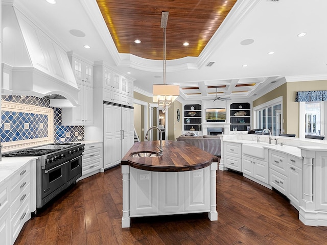 5132 Jungle Plum Rd, Sarasota, FL 34242 - kitchen featuring range with two ovens, a sink, custom range hood, an island with sink, and crown molding