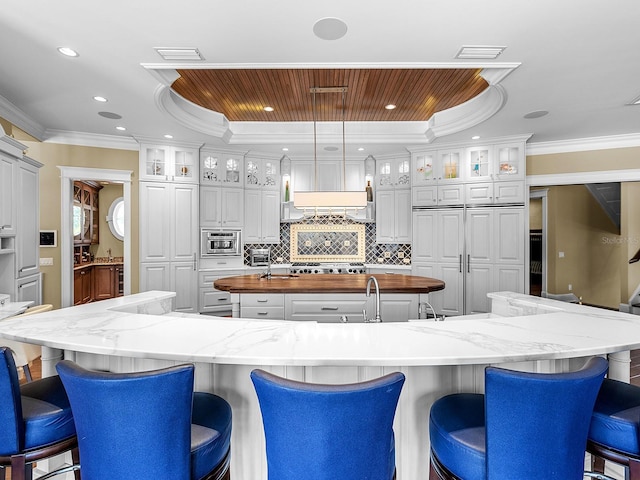 5132 Jungle Plum Rd, Sarasota, FL 34242 - kitchen featuring a large island with sink, tasteful backsplash, a breakfast bar area, wooden counters, and stainless steel gas cooktop