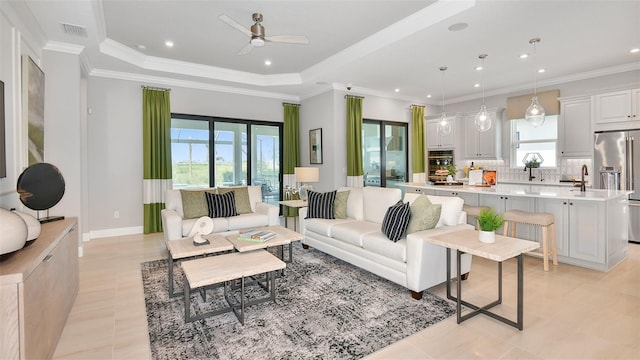 living room with a tray ceiling, visible vents, light tile patterned flooring, and a ceiling fan