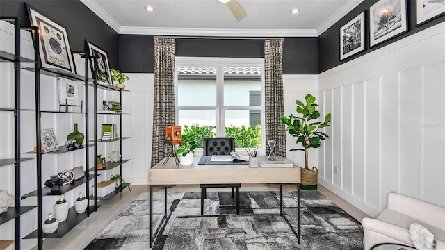 office space featuring wood finished floors, a ceiling fan, crown molding, a decorative wall, and wainscoting