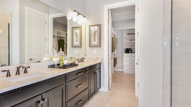 bathroom with tile patterned floors, double vanity, a sink, and a walk in closet