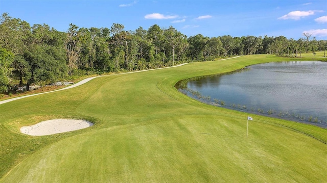 view of community with a water view, a yard, and view of golf course