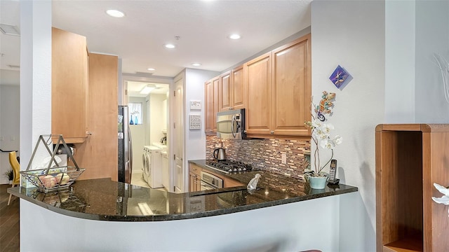 235 Cocoanut Ave Unit 108B, Sarasota, FL 34236 - kitchen featuring stainless steel appliances, independent washer and dryer, decorative backsplash, light brown cabinets, and dark stone counters