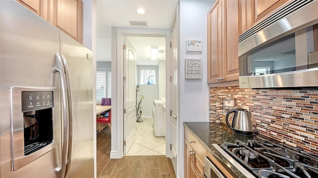 235 Cocoanut Ave Unit 108B, Sarasota, FL 34236 - kitchen with stainless steel appliances, washer and clothes dryer, tasteful backsplash, dark stone counters, and light brown cabinets