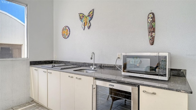 235 Cocoanut Ave Unit 108B, Sarasota, FL 34236 - kitchen with wine cooler, a sink, white cabinets, dark stone countertops, and light tile patterned flooring