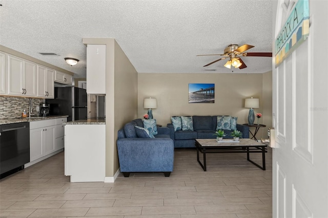 living room with ceiling fan, light wood-style floors, and a textured ceiling