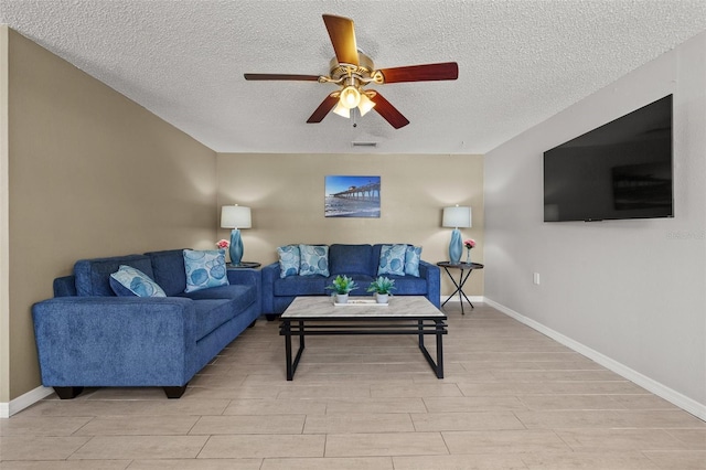 living area with a ceiling fan, a textured ceiling, light wood-type flooring, and baseboards