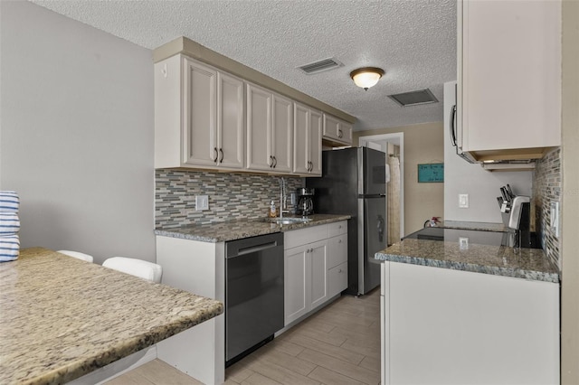 kitchen with dishwasher, a sink, range, a textured ceiling, and decorative backsplash