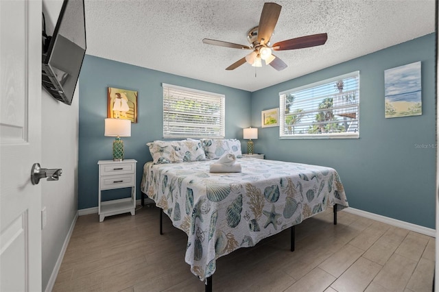 bedroom featuring wood finished floors, baseboards, a textured ceiling, and ceiling fan