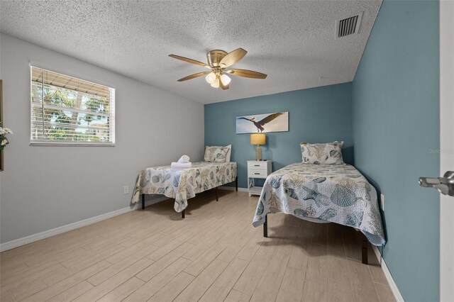 bedroom with wood finished floors, a textured ceiling, baseboards, and a ceiling fan