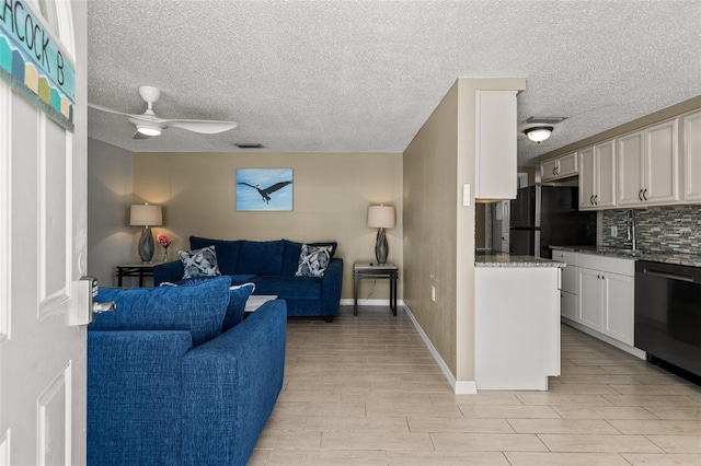 living area featuring a ceiling fan, light wood-style flooring, and a textured ceiling