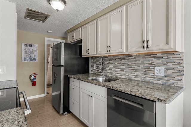kitchen with stainless steel appliances, a sink, light wood-style flooring, baseboards, and decorative backsplash