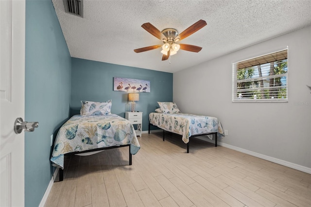 bedroom featuring a textured ceiling, baseboards, wood finished floors, and a ceiling fan