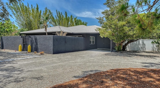 view of front facade with fence, a tiled roof, and stucco siding