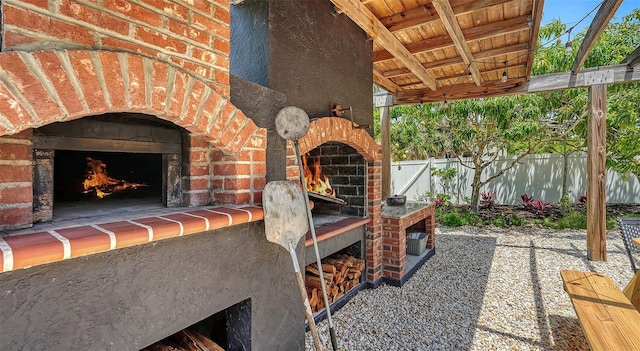view of patio featuring an outdoor brick fireplace and fence