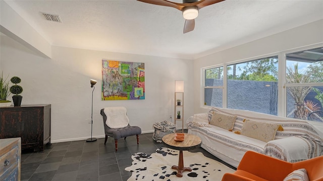 living room with ceiling fan and baseboards