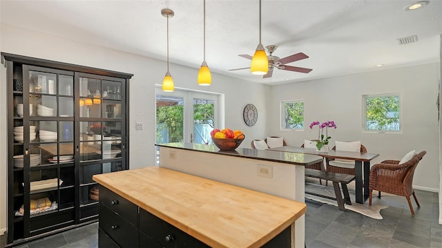 kitchen with butcher block counters, a center island, dark cabinetry, and a ceiling fan