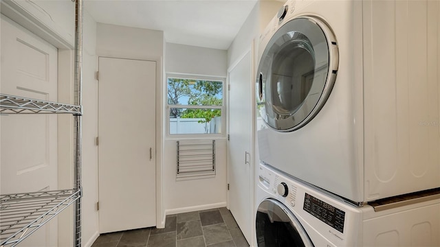 washroom with estacked washer and dryer and baseboards