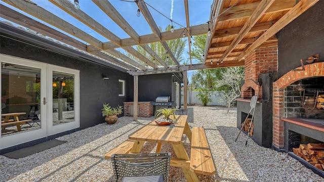 view of patio with an outdoor brick fireplace, french doors, fence, and a pergola