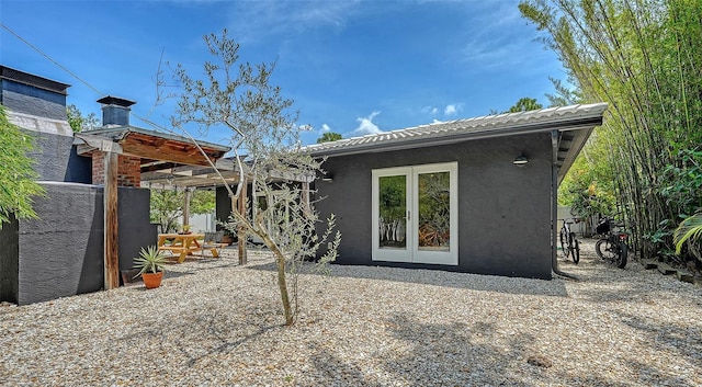 rear view of property featuring stucco siding, fence, french doors, and a patio