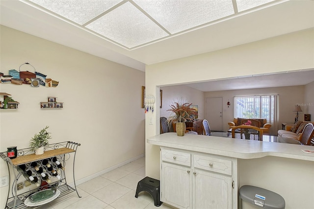 3705 S School Ave Unit 3, Sarasota, FL 34239 - kitchen with light countertops, light tile patterned floors, open floor plan, white cabinets, and a peninsula