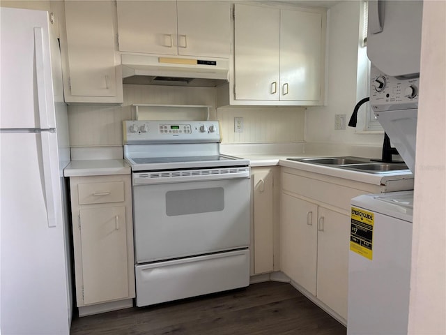 kitchen featuring white appliances, under cabinet range hood, light countertops, stacked washer and clothes dryer, and dark wood-style floors