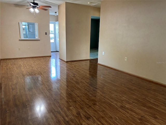 unfurnished room featuring ceiling fan, wood finished floors, and baseboards