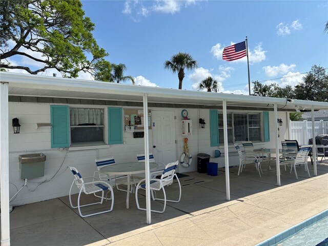 rear view of property featuring outdoor dining space, a patio, and fence