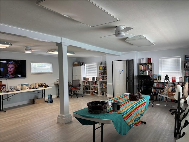 basement with ceiling fan, light wood-style floors, and a desk
