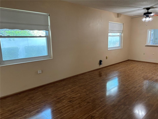 unfurnished room with plenty of natural light, wood finished floors, a ceiling fan, baseboards, and a textured ceiling