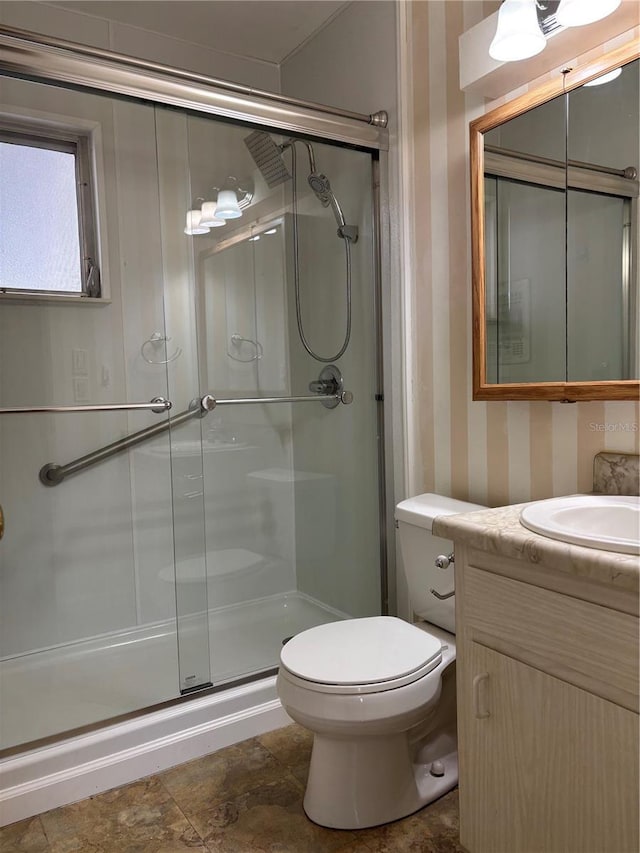 full bath featuring a shower stall, wallpapered walls, vanity, and toilet