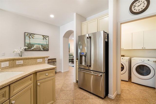 20040 Rookery Dr, Estero, FL 33928 - kitchen with stainless steel refrigerator with ice dispenser, washing machine and clothes dryer, cream cabinets, arched walkways, and light tile patterned floors
