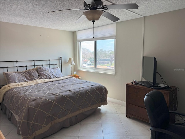 bedroom featuring a textured ceiling, light tile patterned flooring, a ceiling fan, and baseboards
